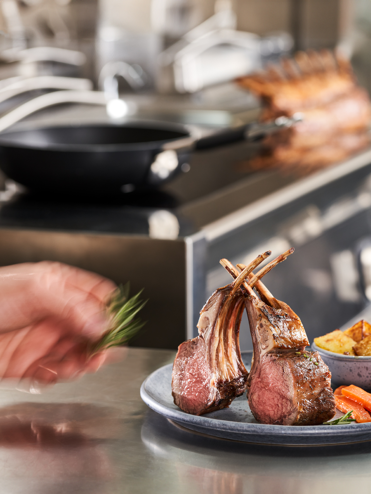 Chef che decora un piatto con due costolette di agnello