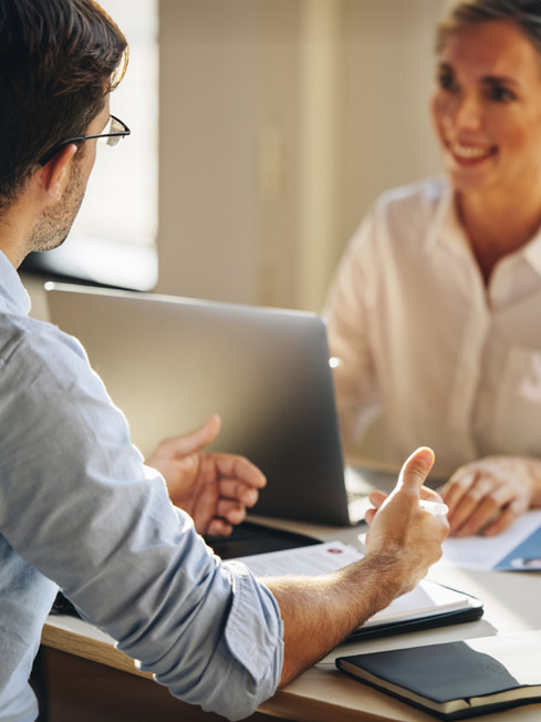 un uomo e una donna felici parlano tra di loro mentre sono seduti a una scrivania