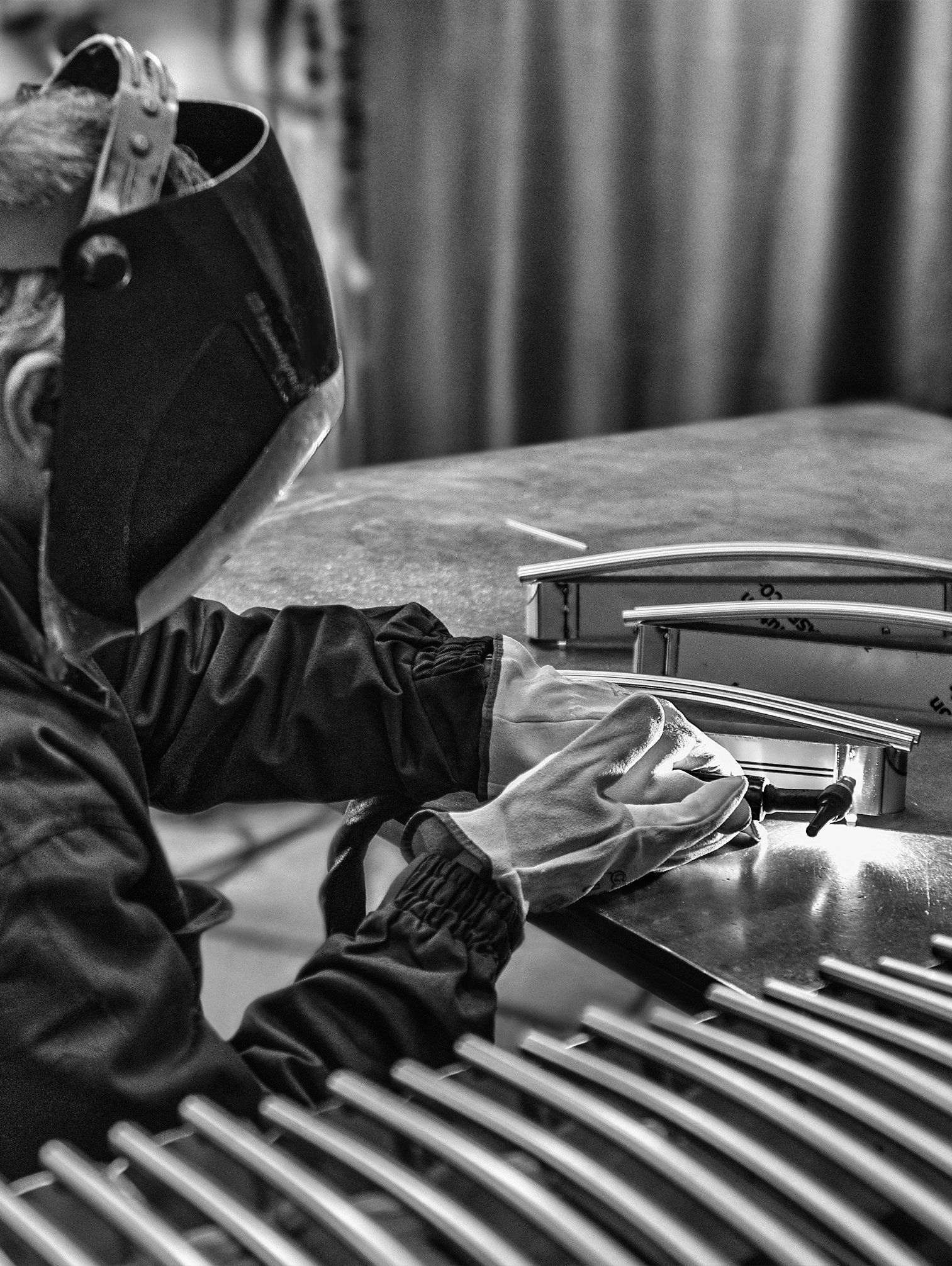 uomo con la maschera per la saldatura che lavora su alcuni pezzi di alluminio