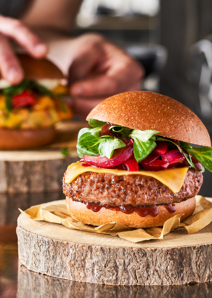 panino hamburger cucinato e appena servito su un piatto fatto di legno