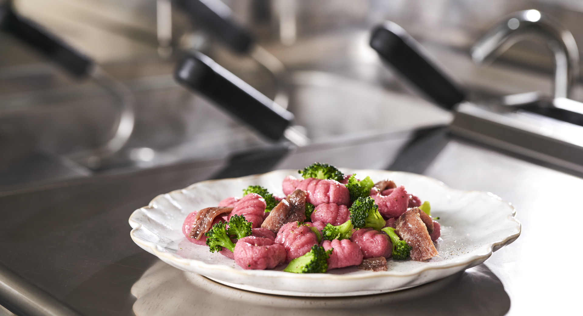 Piatto di gnocchi di barbabietola conditi con broccoli e acciughe
